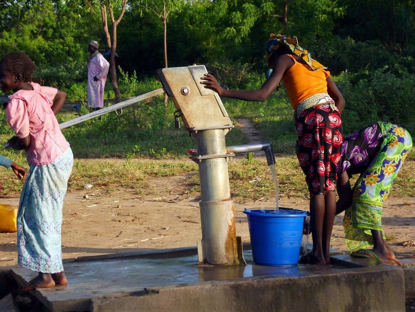 Women and children collect water from a hand pump in Cameroon.